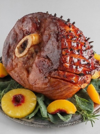 Christmas ham on platter with salad and peaches